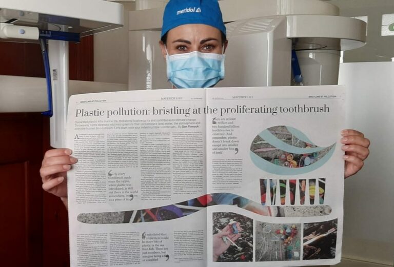 Oral Hygienist, Chrismarie Barnardt, holding up a newspaper featuring the Kindbrush Story.